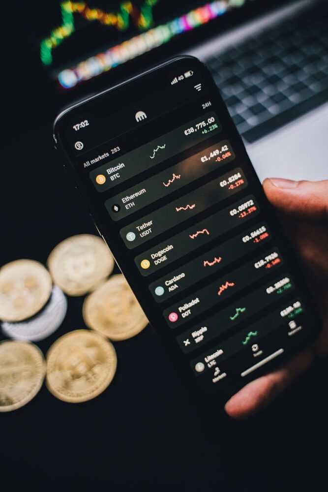 Close-up of a smartphone showing cryptocurrency trends with coins in the background.