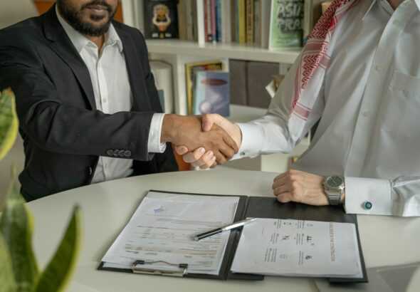 a couple of men shaking hands over a desk