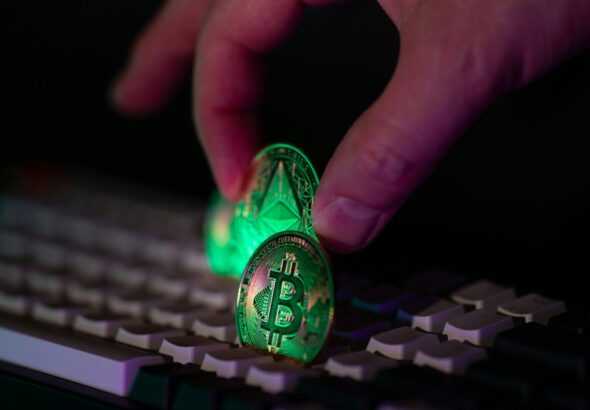 Hand placing glowing crypto coins on a keyboard.