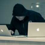 man in black hoodie using macbook