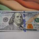 a stack of one hundred dollar bills sitting on top of a table