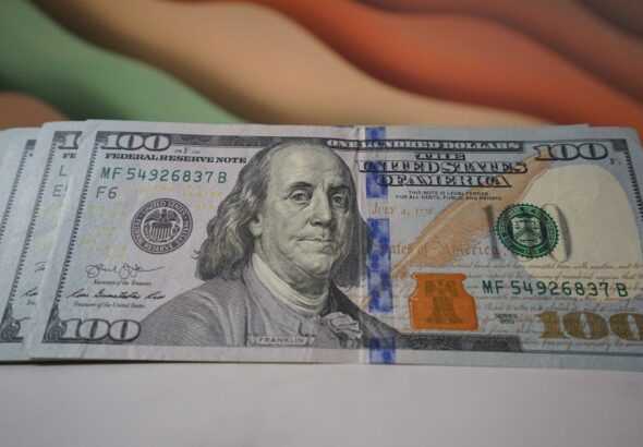 a stack of one hundred dollar bills sitting on top of a table