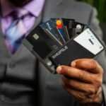 a man in a suit holding four credit cards